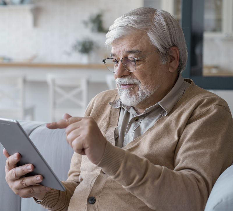 Man zit op een bank naar een tablet te kijken.