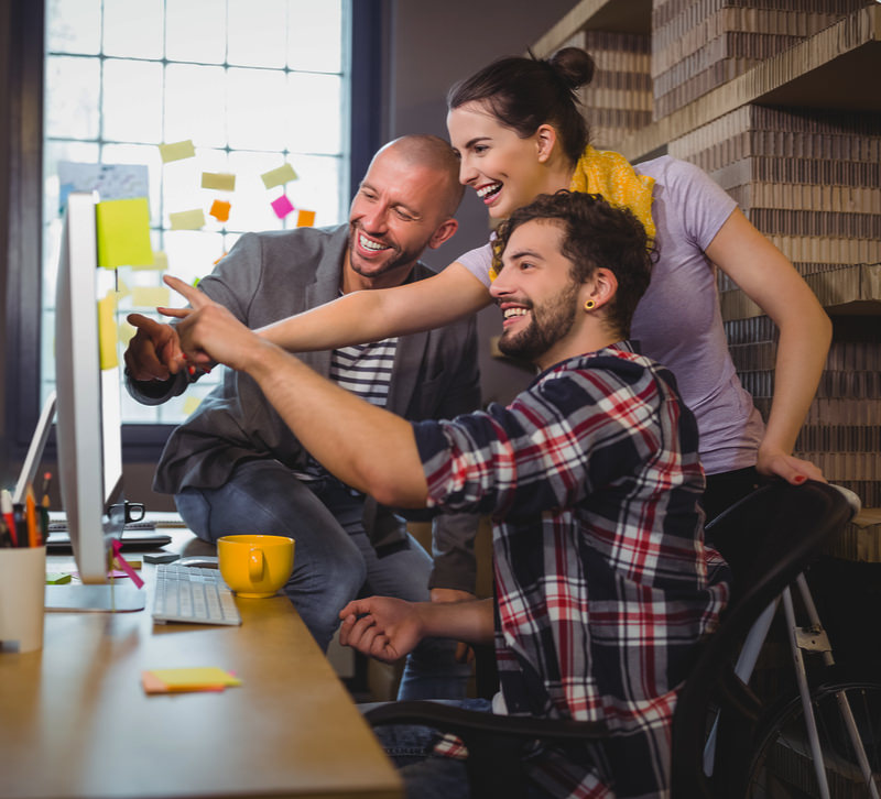 2 mannen en 1 vrouw kijken naar een monitor met een website in de AllMediaLab webdesign studio.