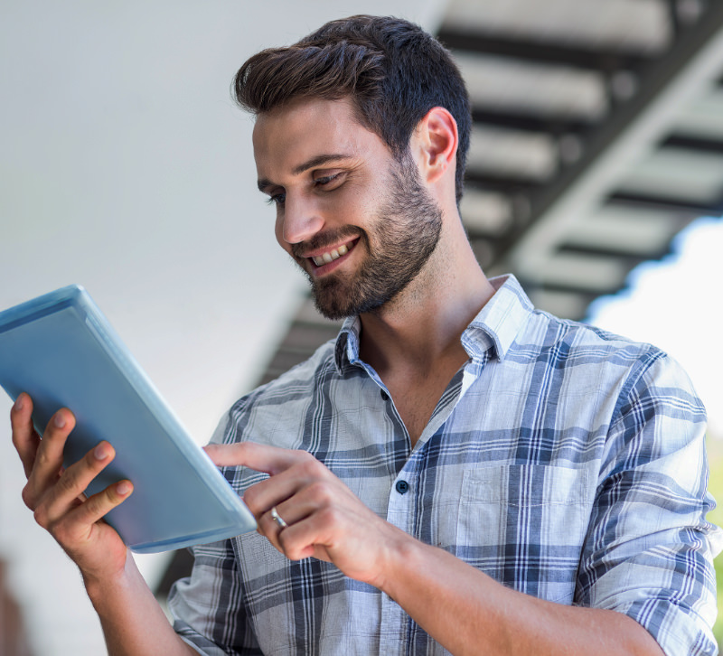 Een man kijkt heel blij naar zijn tablet met daarop zijn nieuwe website, gemaakt door AllMediaLab webdesign.