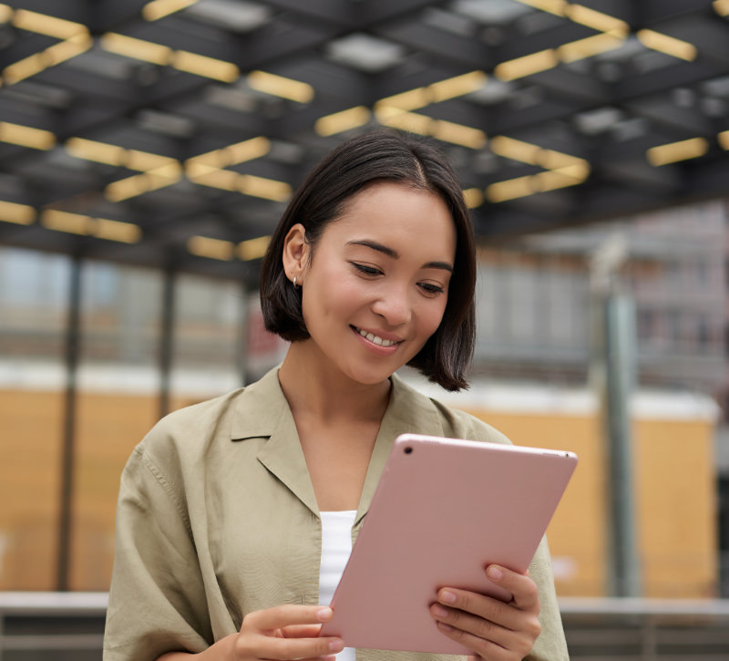 Woman stands in a very large room looking at her tablet with her new website.