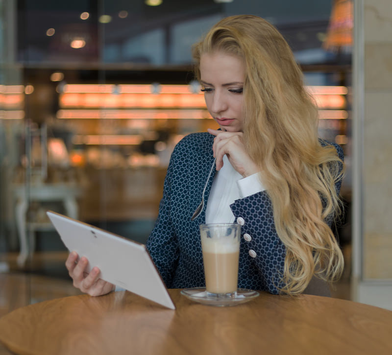 Een stijlvol geklede vrouw kijkt op haar tablet naar haar nieuwe website gemaakt door AllMediaLab webdesign
