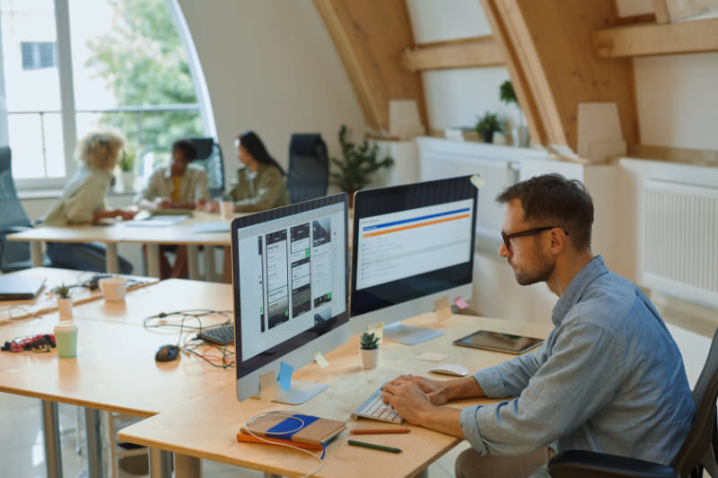 Man met baardje zit een e-mail ontwerp te maken achter een monitor bij AllMediaLab webdesign